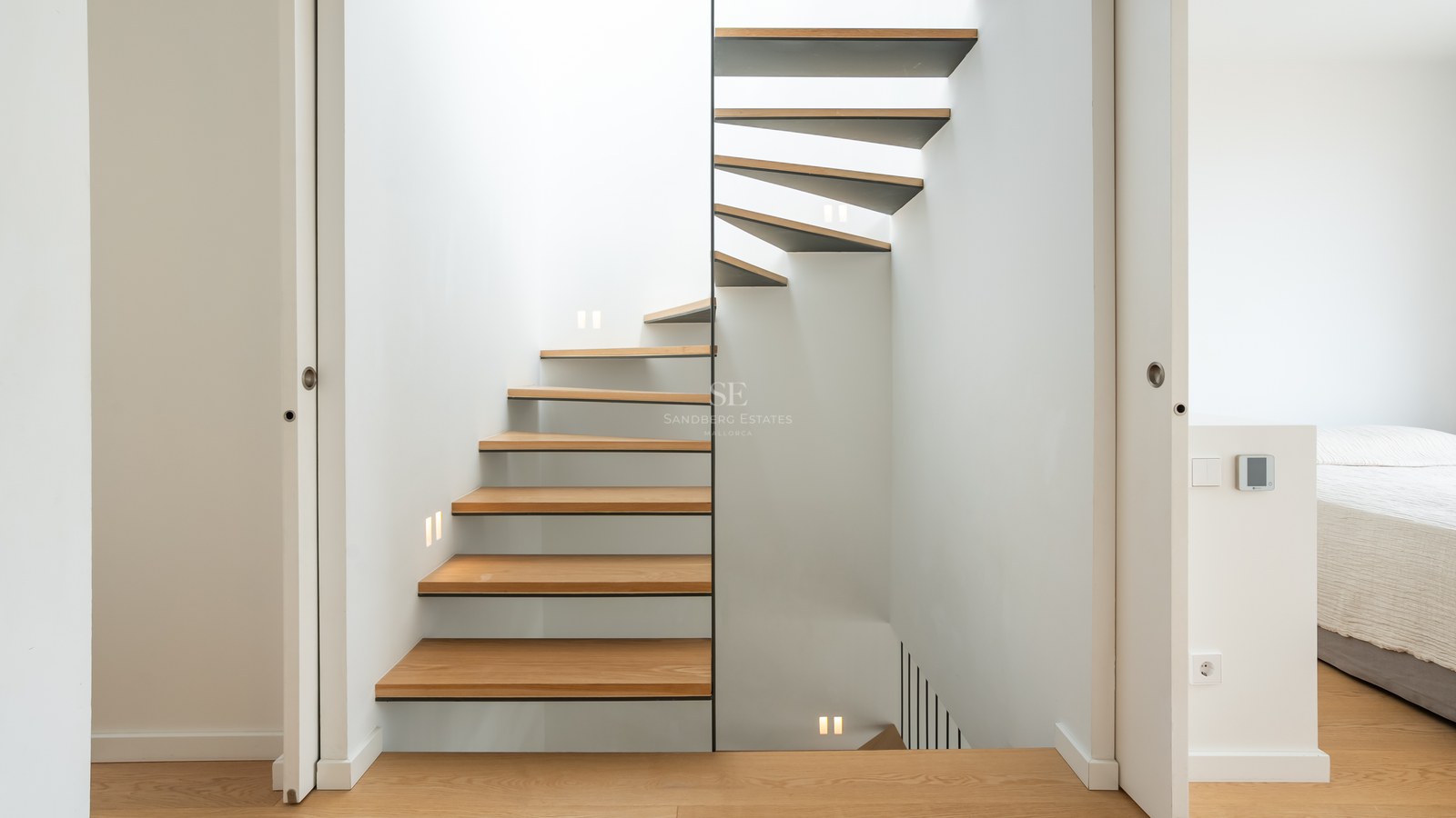 Escalier en colimaçon moderne avec marches en chêne et éclairage LED mural intégré.