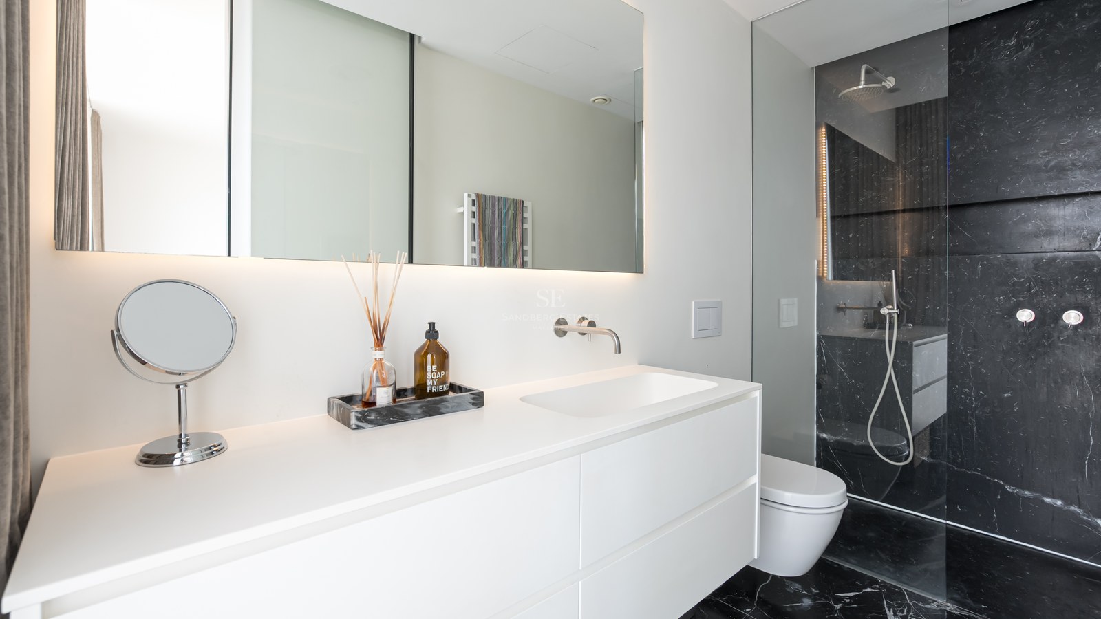Salle de bain minimaliste blanche avec meuble vasque suspendu et douche à l'italienne en marbre noir.