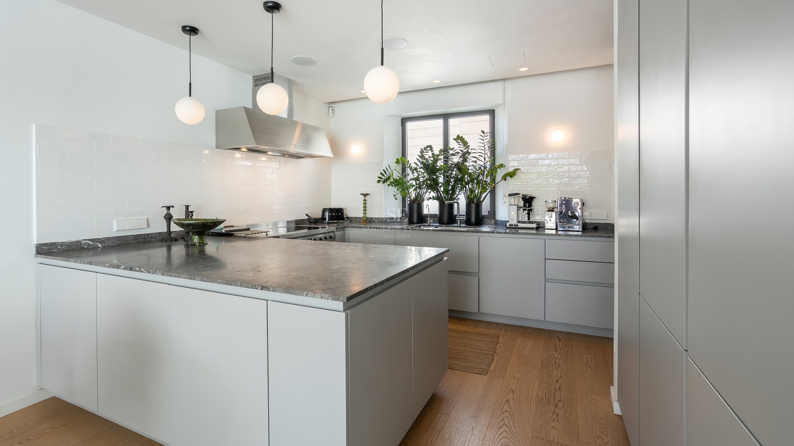 Cuisine contemporaine avec grand îlot en marbre gris, armoires grises minimalistes et suspensions globes blancs.