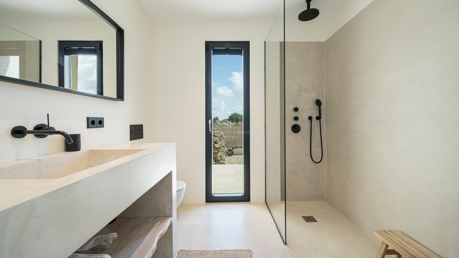 Salle de bain moderne avec plan vasque en microciment, douche à l'italienne et robinetterie noir mat.
