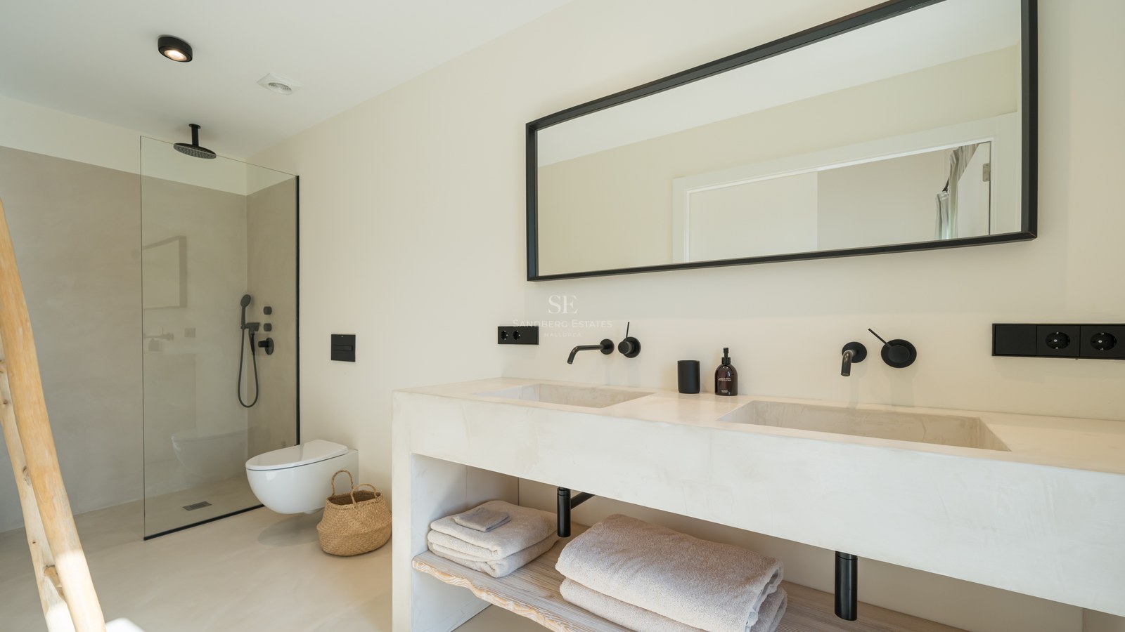 Salle de bains minimaliste avec double vasque, robinetterie noire mate, douche à l'italienne et finitions microciment.