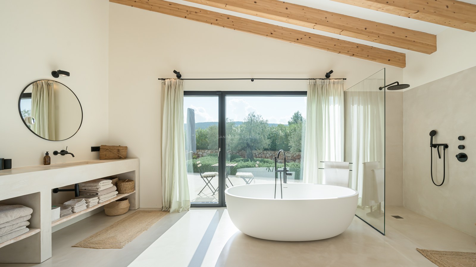 Salle de bain moderne avec baignoire îlot, poutres en bois, douche à l'italienne et accès terrasse paysagée.
