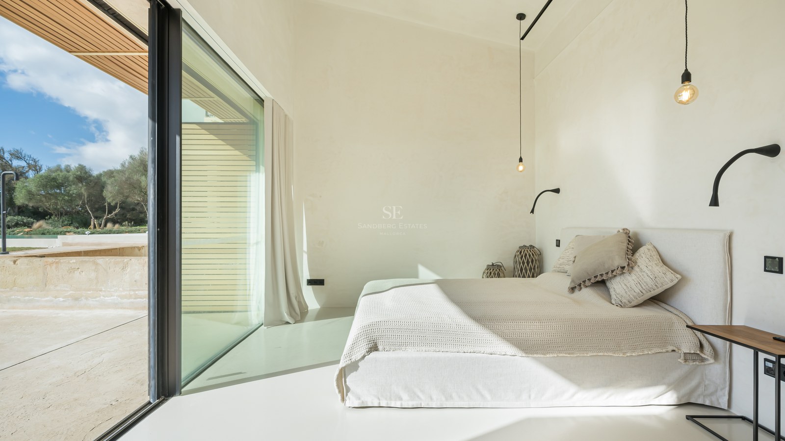 Chambre minimaliste lumineuse avec murs blancs, grande baie vitrée et literie aux tons neutres.