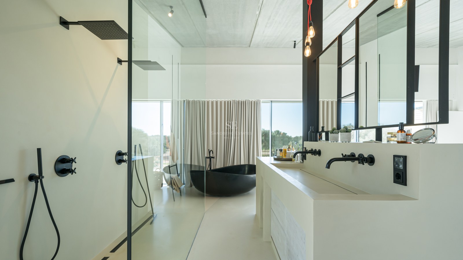 Salle de bains minimaliste avec baignoire îlot noire, double vasque blanche et grandes baies vitrées.