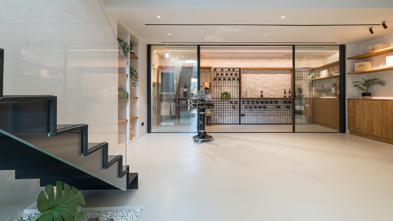 Cave à vin moderne vitrée avec mur en pierre, étagères sur mesure et escalier minimaliste dans une villa de luxe.