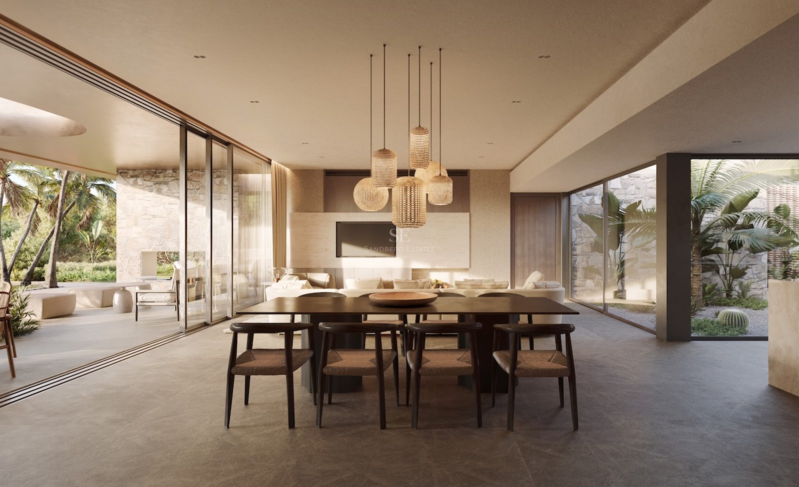 Salle à manger moderne avec table en bois sombre et suspensions en rotin, s'ouvrant sur une terrasse et un jardin.