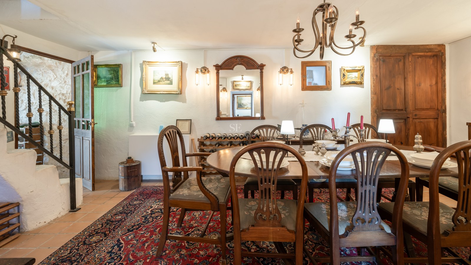 Espace dînatoire formel avec table ovale en bois, chaises de style et tapis oriental rouge.