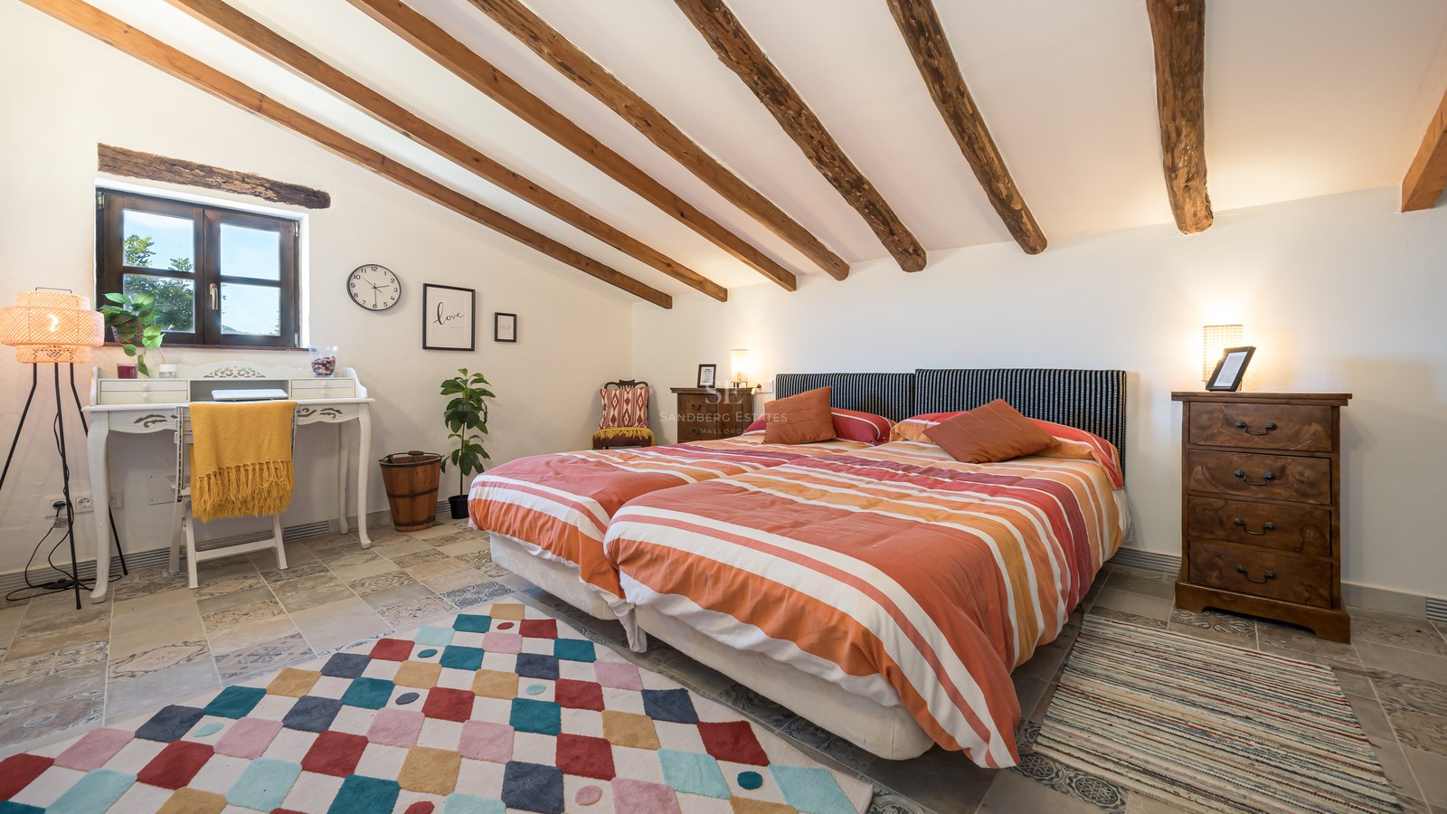 Chambre sous les combles avec poutres en bois, lits jumeaux et revêtement de sol en pierre naturelle.