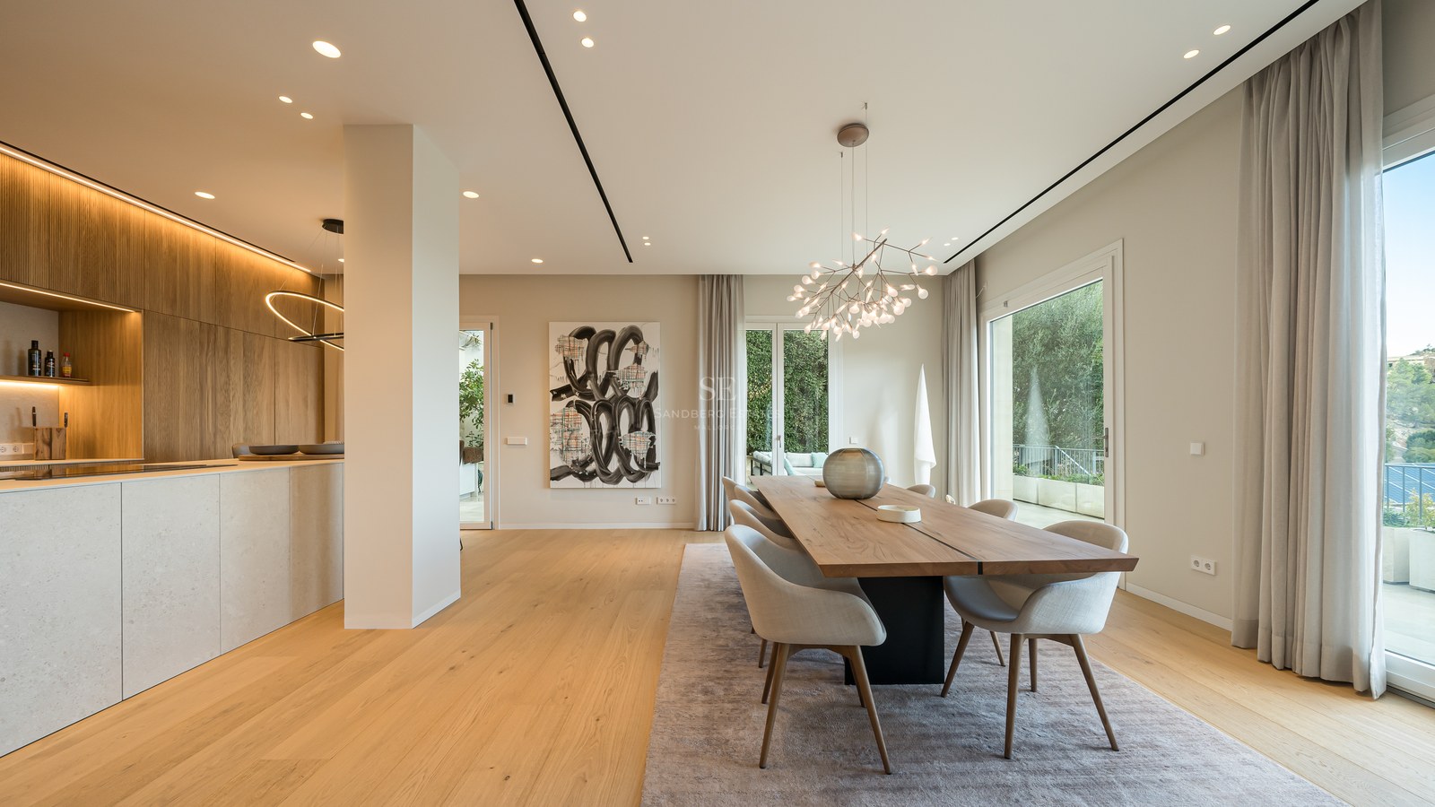 Comedor moderno con mesa de madera, sillas grises, lámpara de diseño y ventanales hacia la terraza.