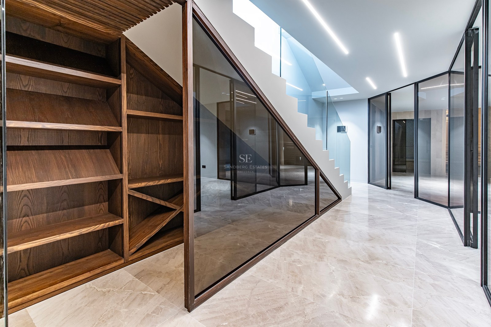 Modern interior with dark wood wine racks, polished marble floors, glass partitions, and a white LED-lit staircase.