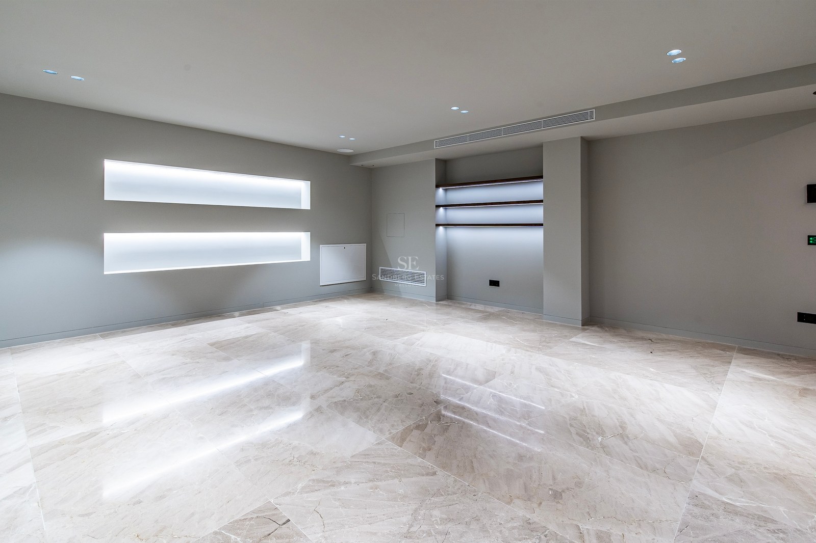 Empty modern room featuring polished marble floors, gray walls, and integrated LED lighting in wall niches.