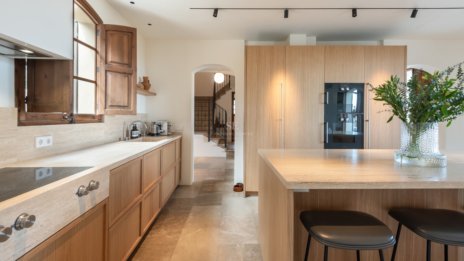 Cuisine contemporaine avec des meubles en bois clair, des plans de travail en pierre naturelle et un îlot central.