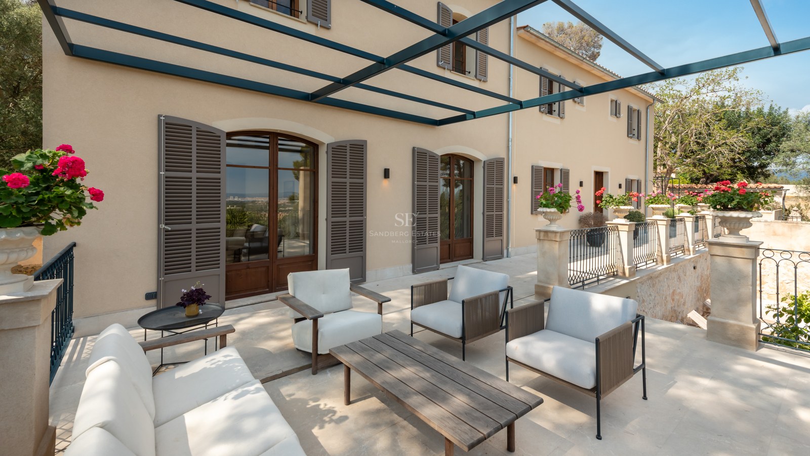 Terrasse de villa de luxe avec mobilier moderne, pergola en métal et volets majorquins traditionnels.