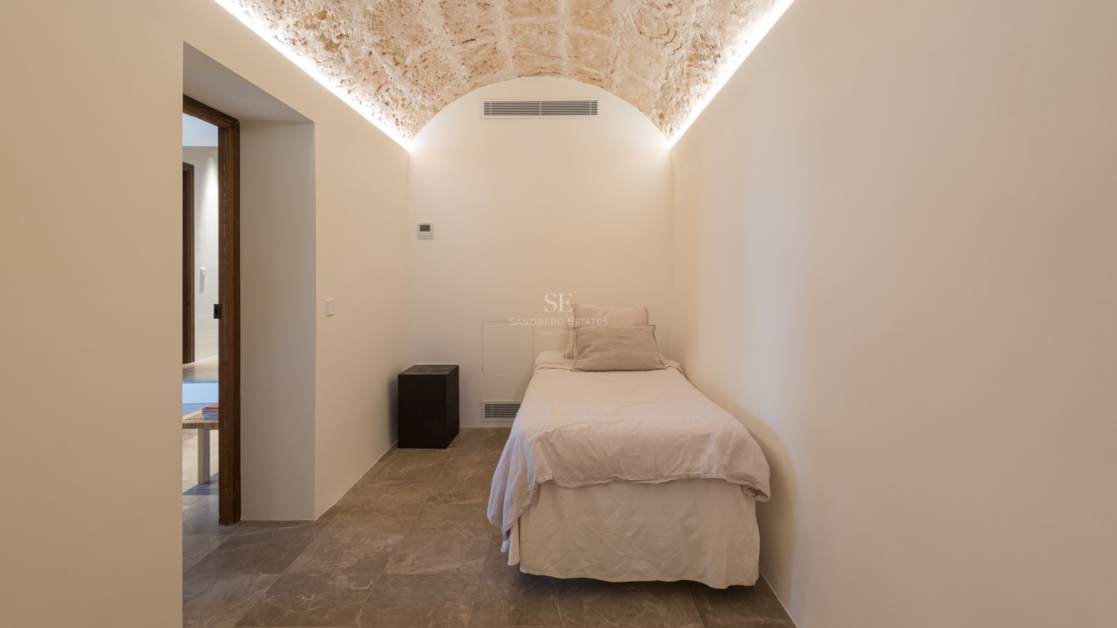 Chambre minimaliste dotée d'un plafond voûté en pierre naturelle avec éclairage indirect et sol en pierre.
