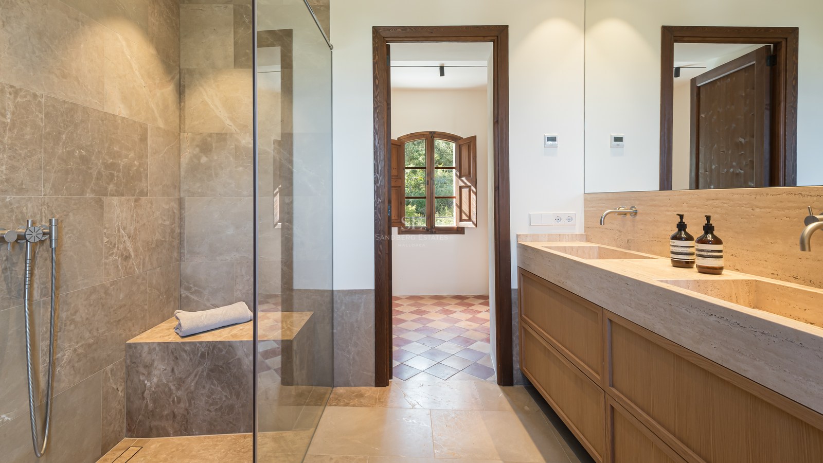 Salle de bains de luxe avec douche à l'italienne en pierre, double vasque intégrée et menuiserie en chêne.