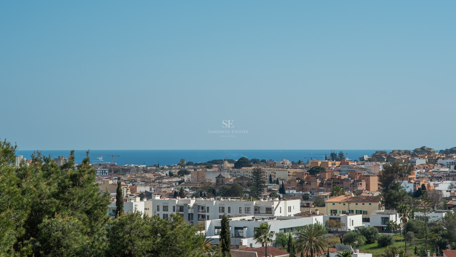 Vue d'en haut d'une ville côtière avec des bâtiments blancs et des toits rouges surplombant la mer Méditerranée.