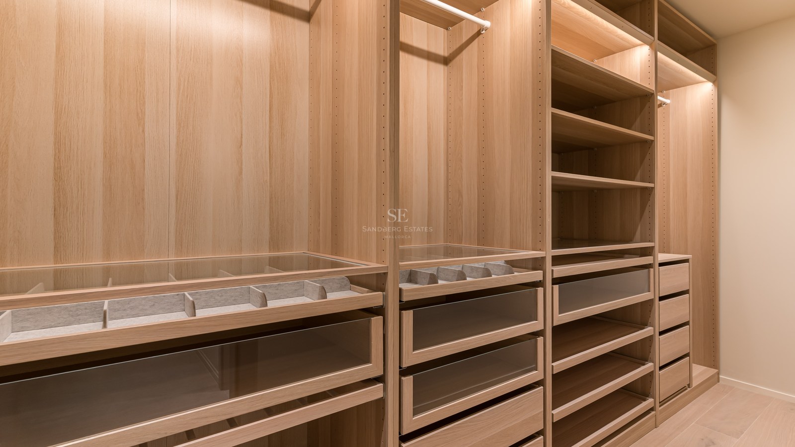 Vestidor moderno de roble claro con cajones de cristal, organizadores de joyas e iluminación LED integrada.