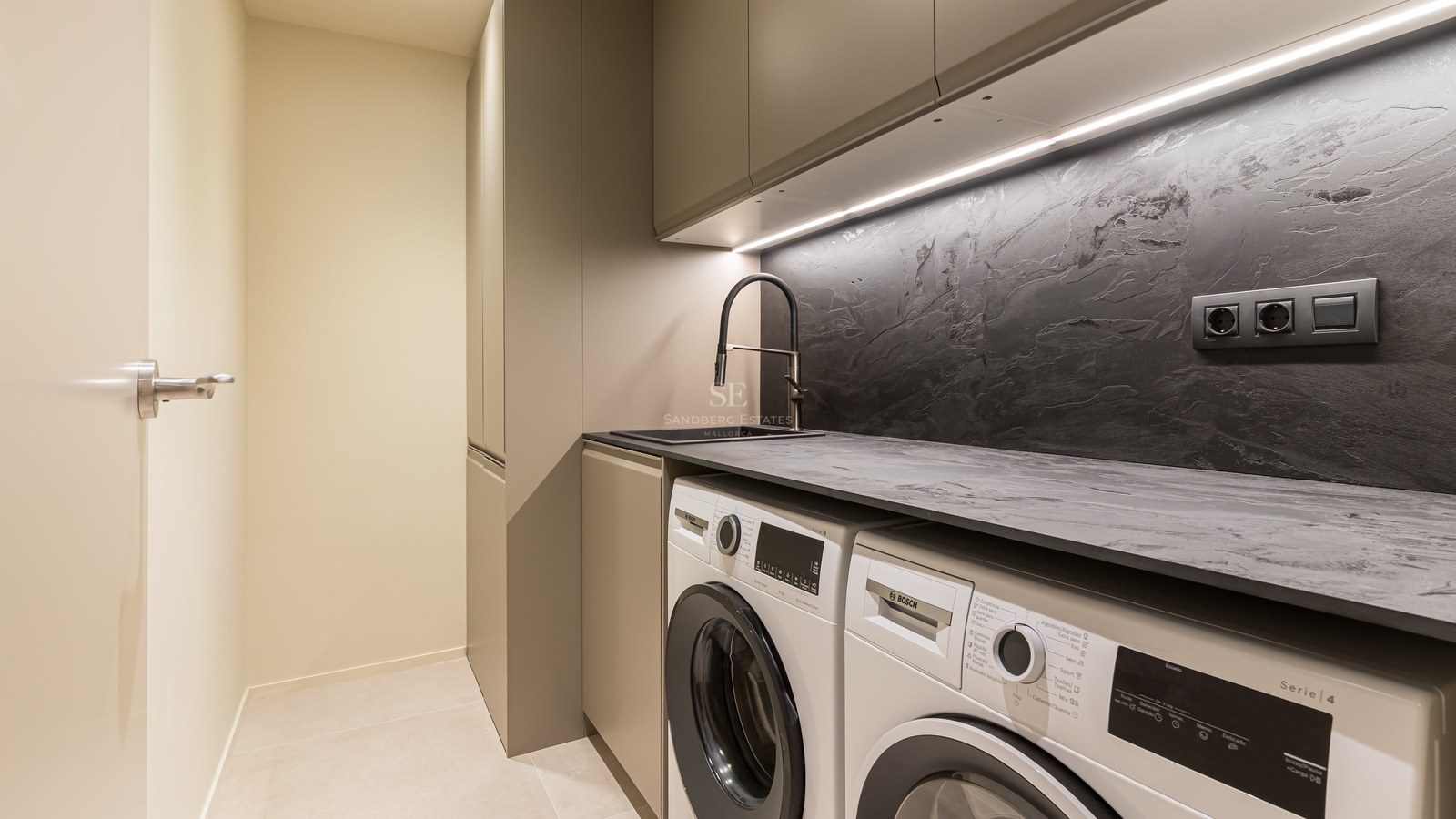 Área de lavandería contemporánea con lavadora y secadora Bosch, salpicadero oscuro texturizado y luces LED.
