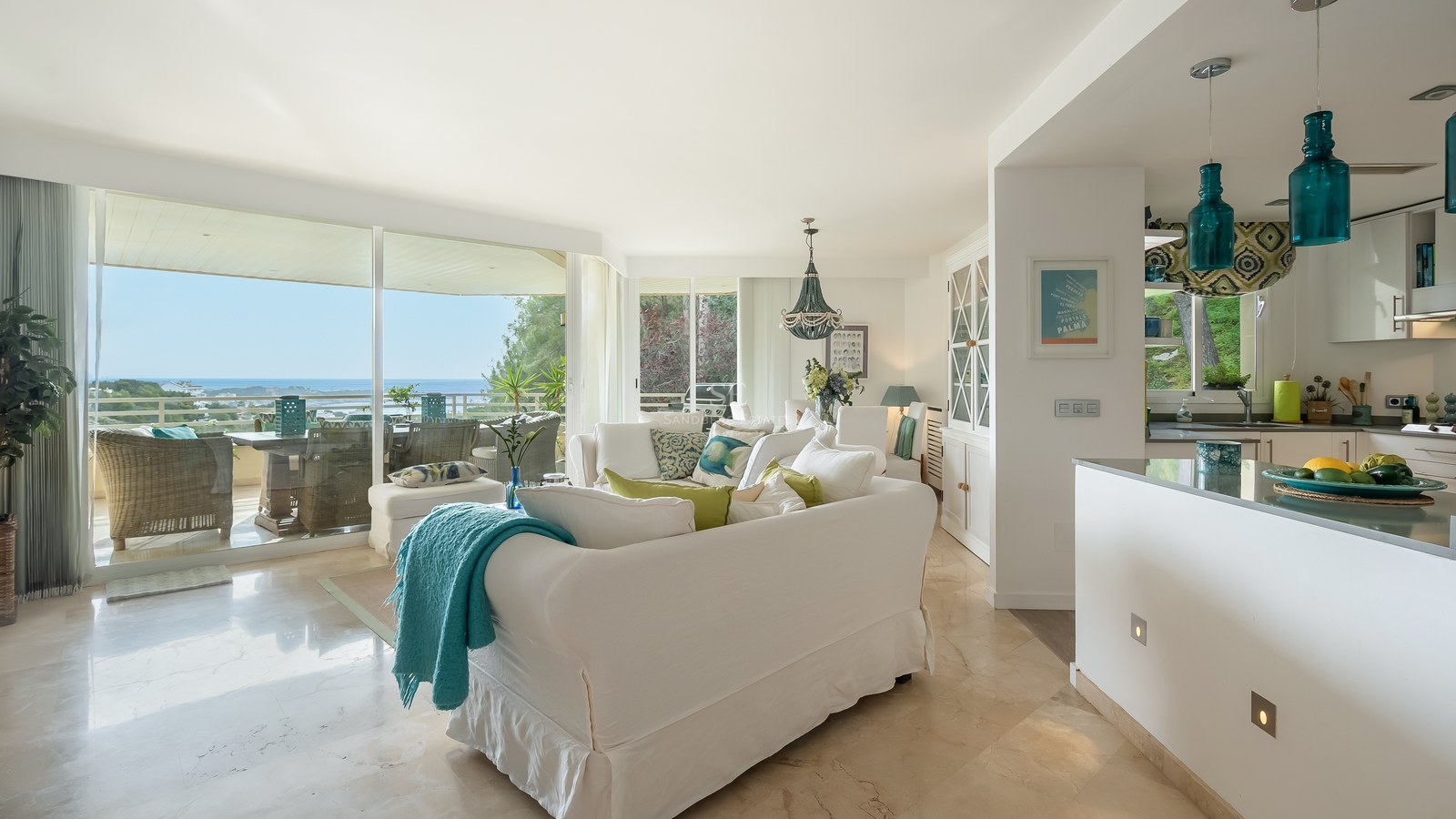Contemporary living room with marble floors, white sofas, and turquoise accents leading to a sea-view terrace.