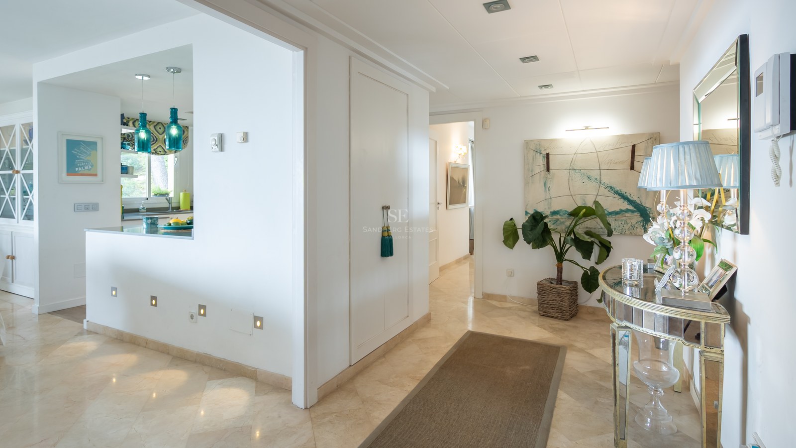 Bright entrance hallway featuring cream marble floors, a mirrored console table, and turquoise glass pendant lights.