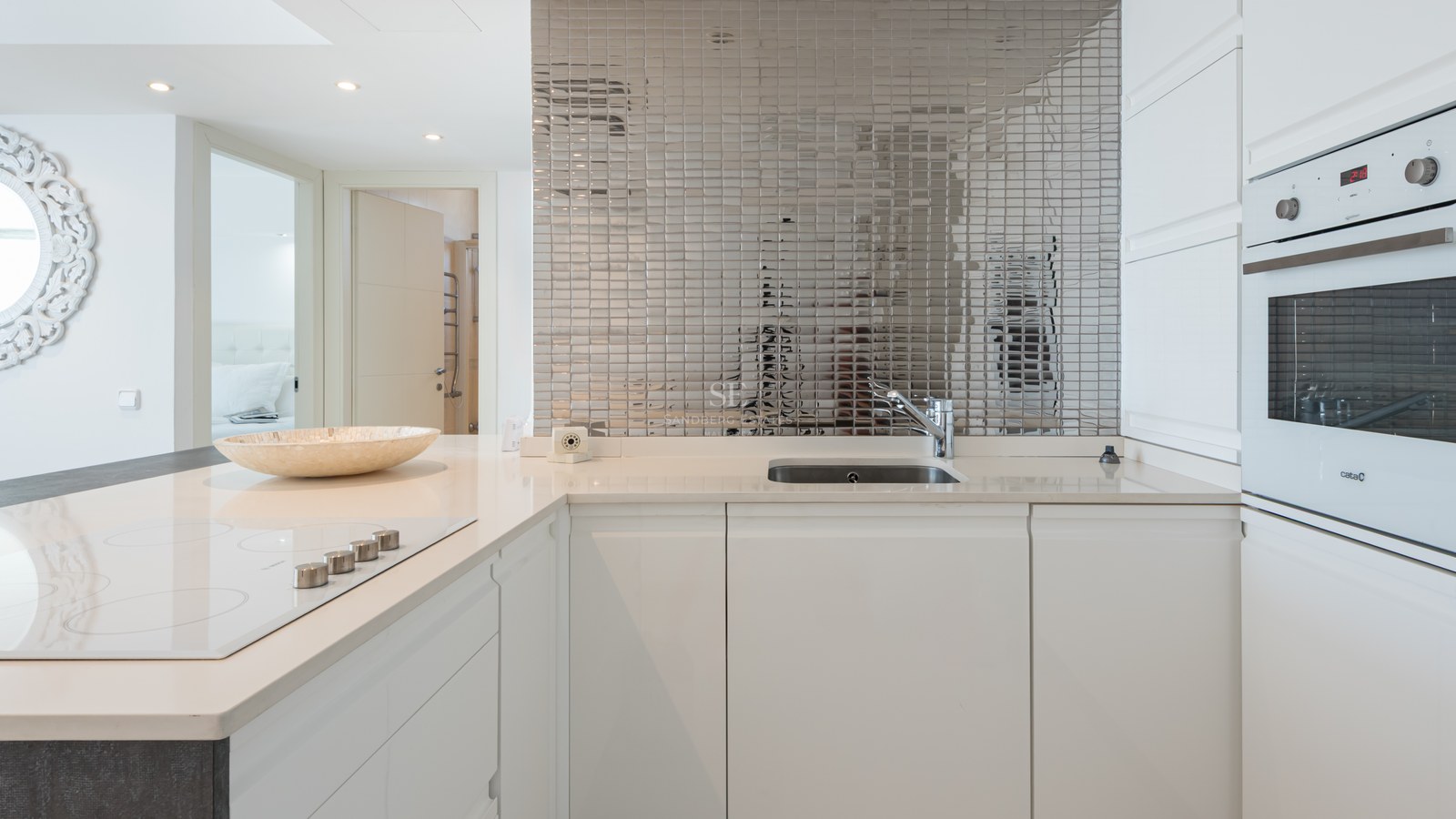 Bright white modern kitchen featuring a mirrored mosaic backsplash, quartz countertops, and integrated appliances.