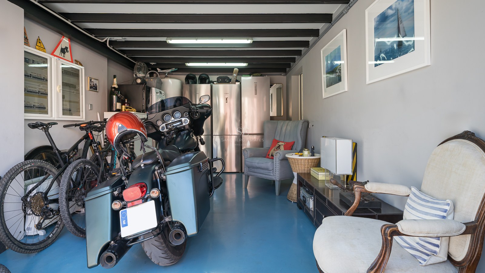 Garageninnenraum mit blauem Epoxidboden, Motorrädern, Fahrrädern und Edelstahlkühlschränken.