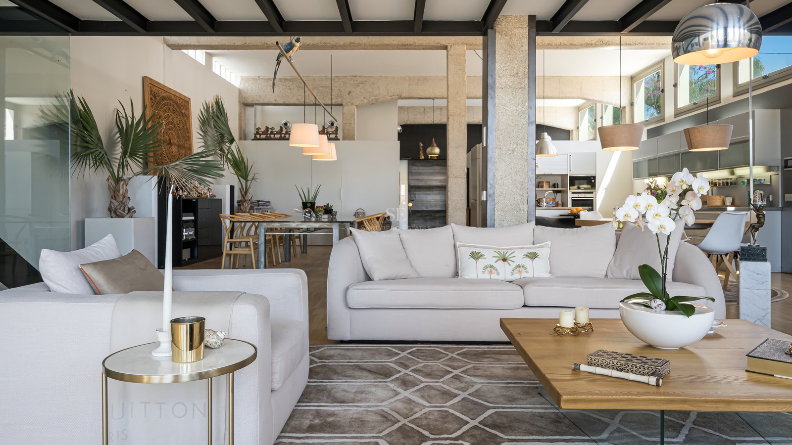 Modernes Wohnzimmer mit weißen Sofas, Sichtbetonpfeilern, schwarzer Industriedecke und hochwertiger Einrichtung.
