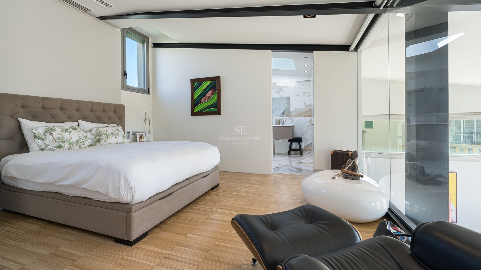 Modernes Schlafzimmer mit Eichenparkett, gepolstertem Kopfteil und Blick in das angrenzende Marmorbad.