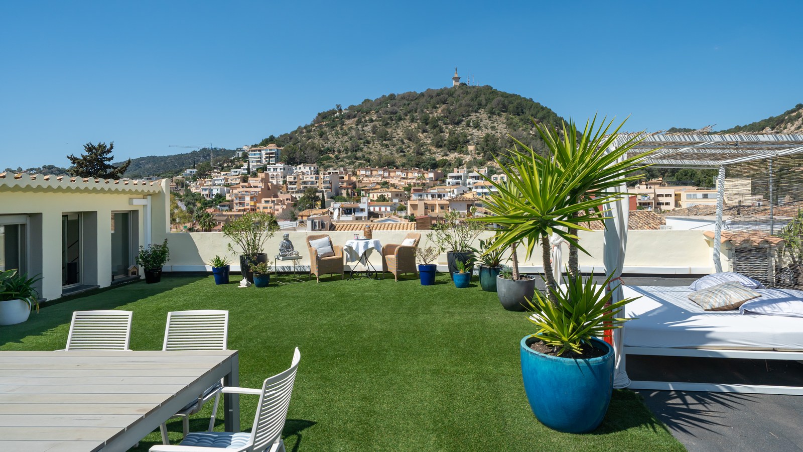 Dachterrasse mit Kunstrasen, Essbereich im Freien, Daybed und Blick auf die mediterrane Hügellandschaft.