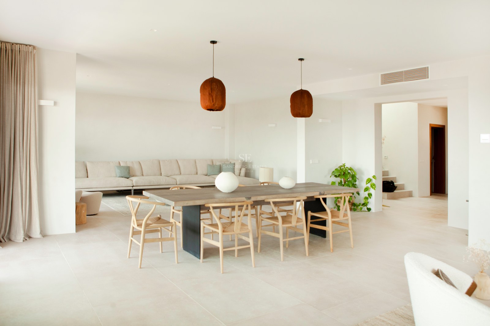 Heller, moderner Essbereich mit großem Holztisch, Wishbone-Stühlen und neutralem Sofa in offenem Grundriss.