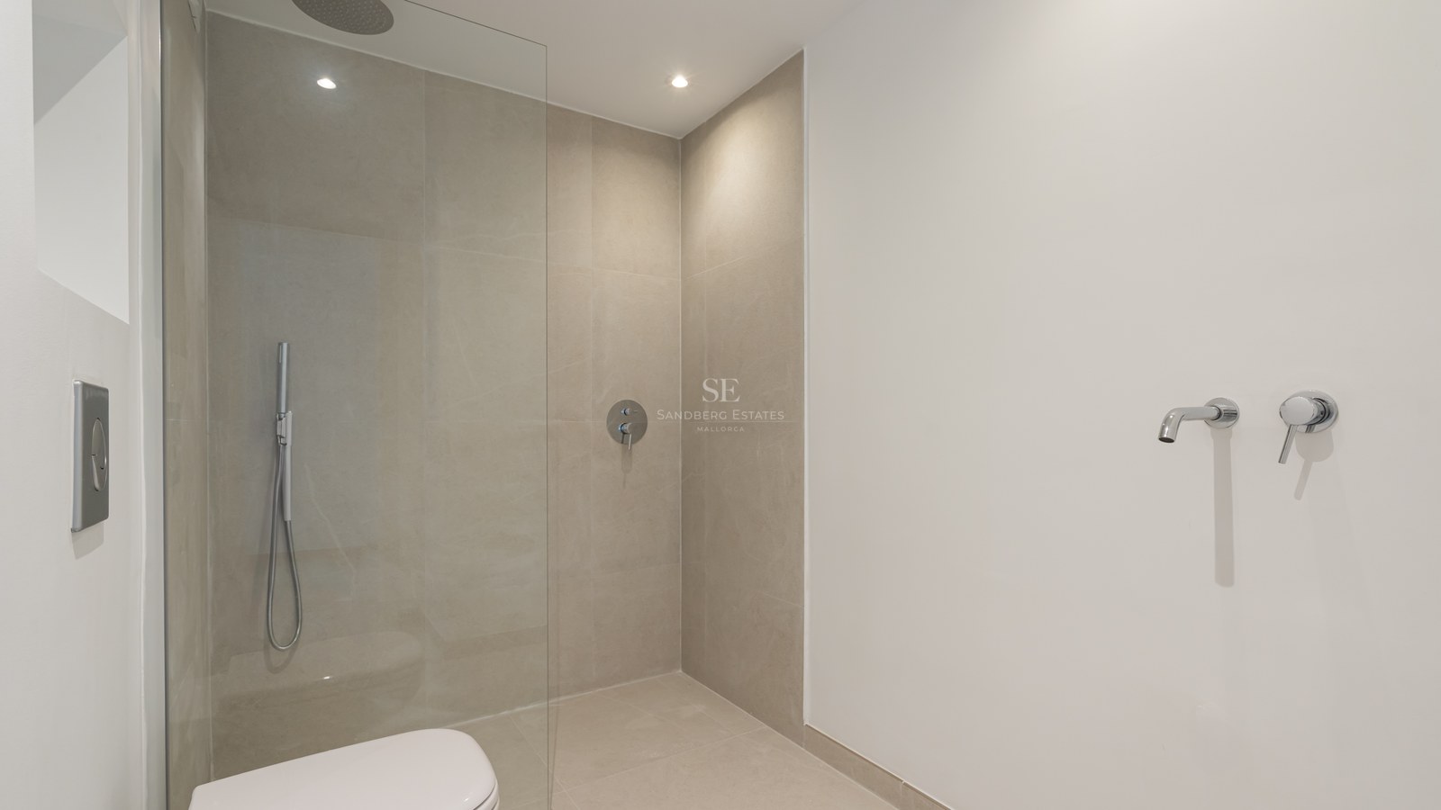 Ducha moderna con mampara de cristal, azulejos beige de gran formato y grifería de cromo empotrada.