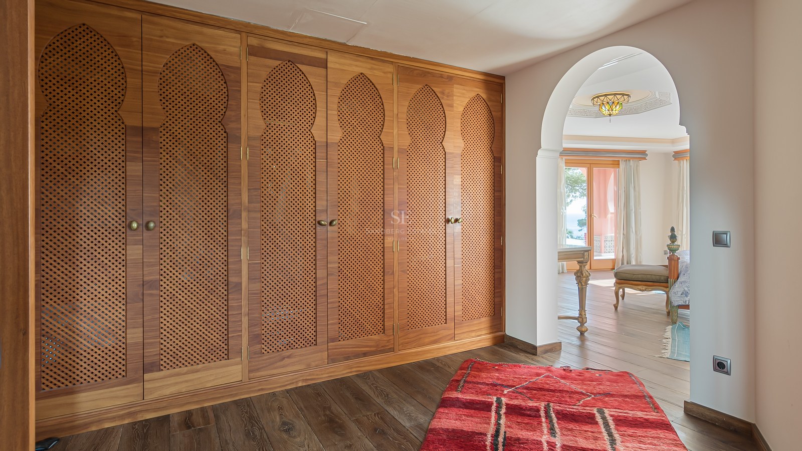 Gros plan de placards en bois du sol au plafond avec des détails d'arches mauresques et parquet foncé.
