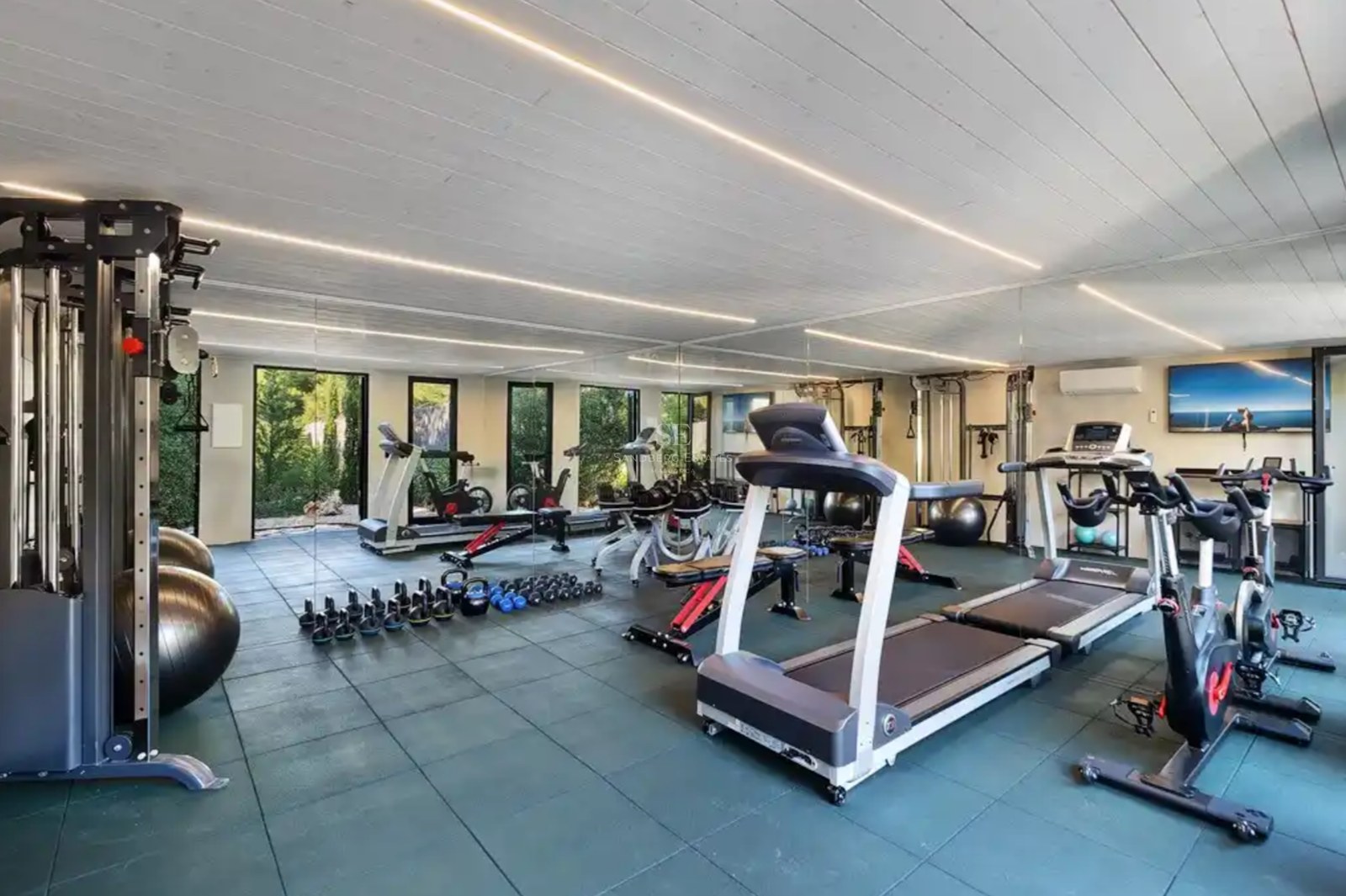 Moderner Heim-Fitnessraum mit Laufbändern, Gewichten und Ganzkörperspiegeln unter linearer LED-Beleuchtung.