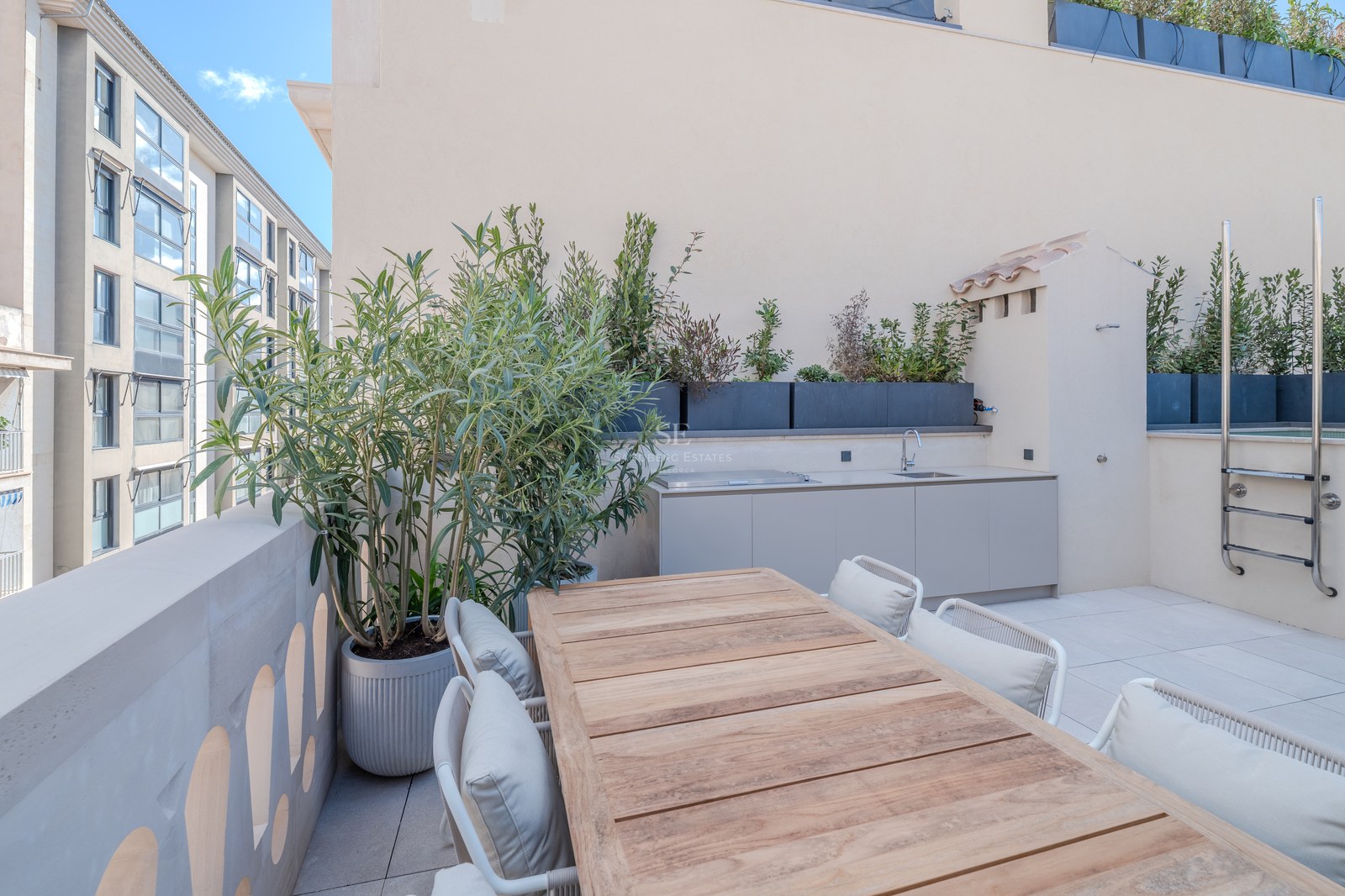 Terrasse moderne sur le toit avec table en bois, kitchenette extérieure et jardinières sous un ciel bleu.