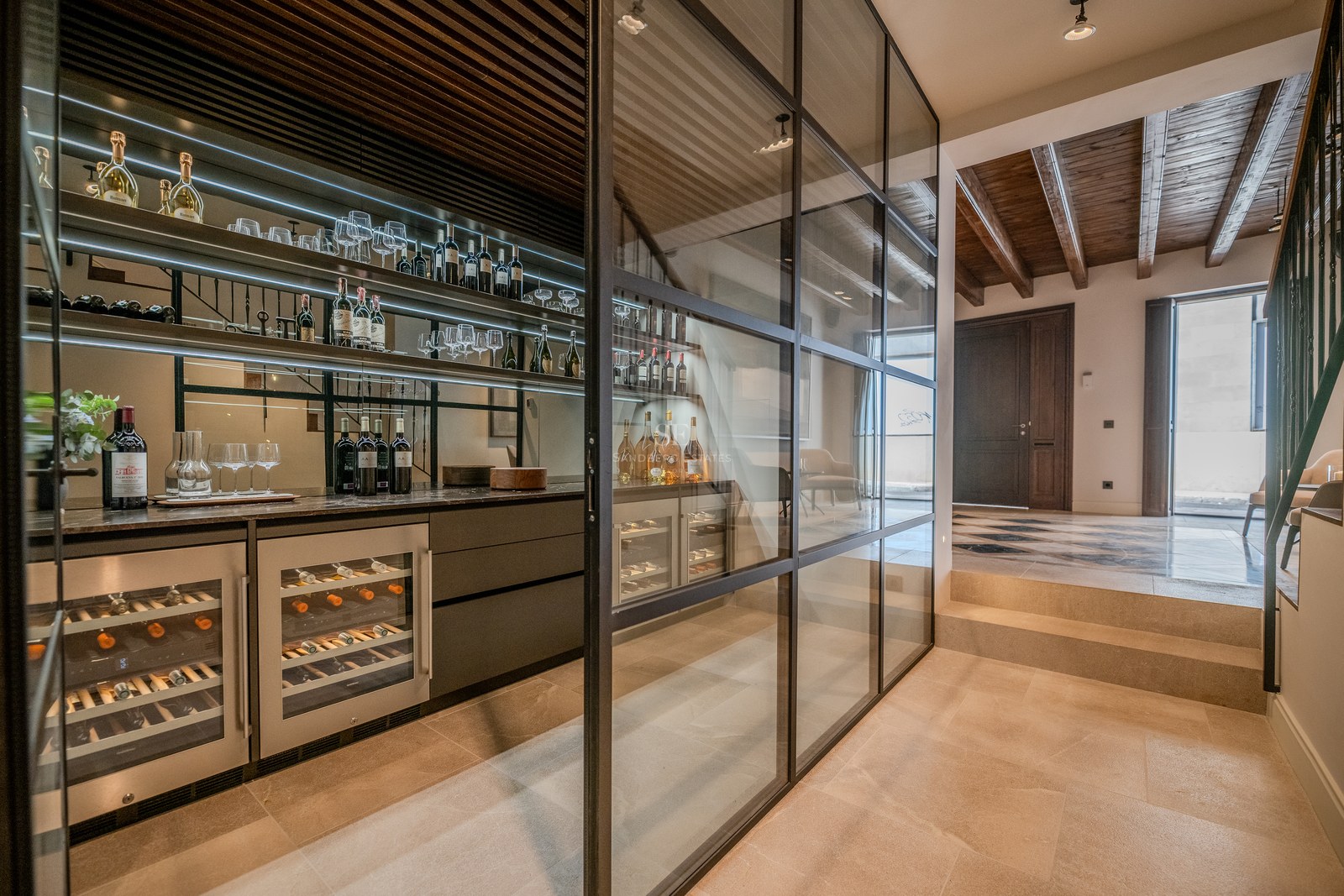 Cave à vin moderne avec parois en verre, cadres noirs, éclairage intégré et armoires à vin professionnelles.