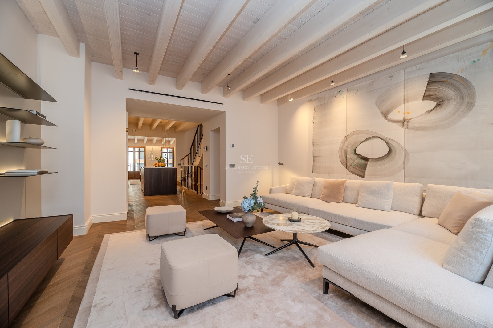 Salon moderne avec canapé crème, table en marbre, poutres en bois apparentes et parquet en point de Hongrie.