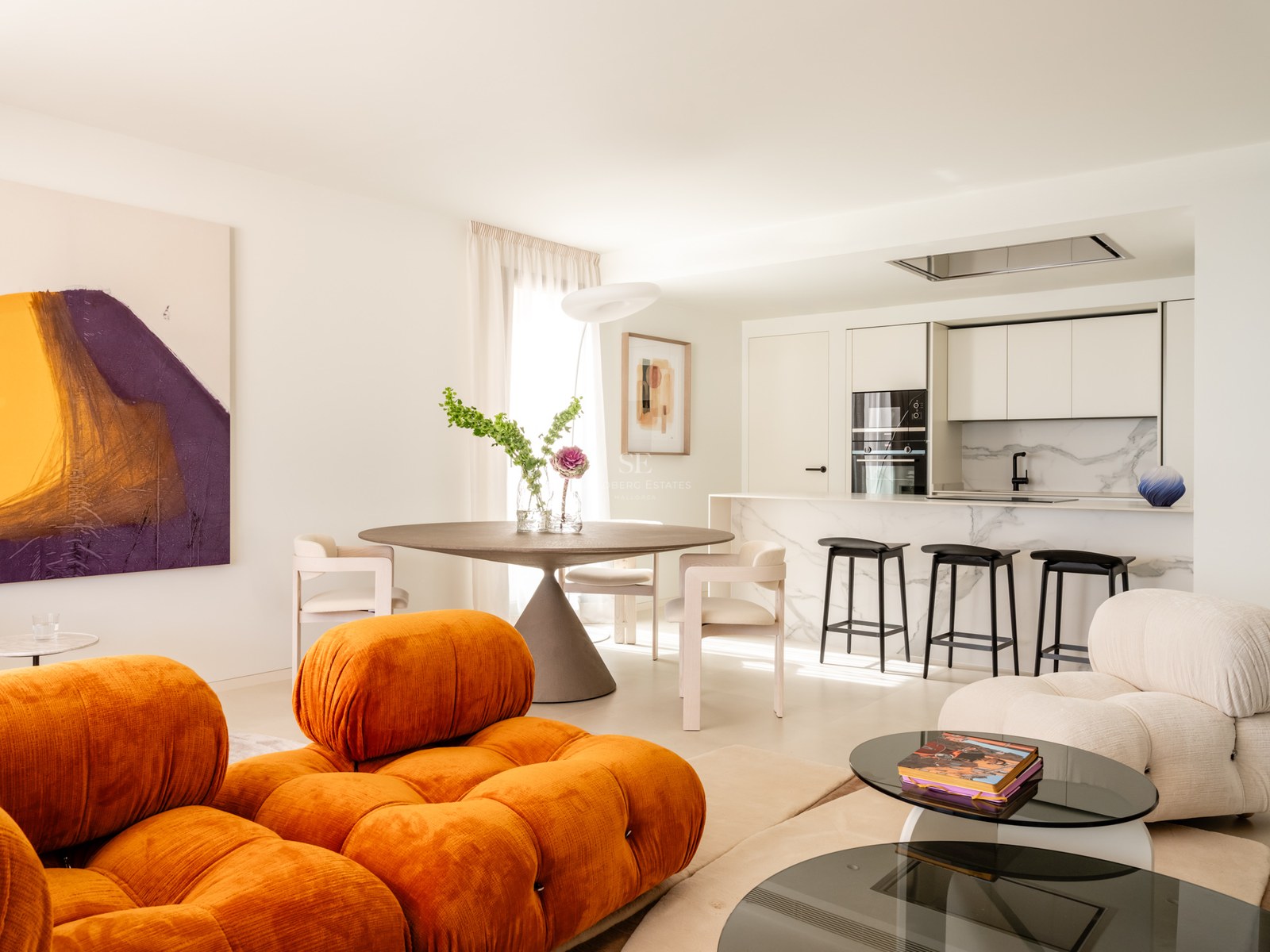 Contemporary living room with orange modular sofa, round dining table, and marble kitchen island in an open-plan layout.