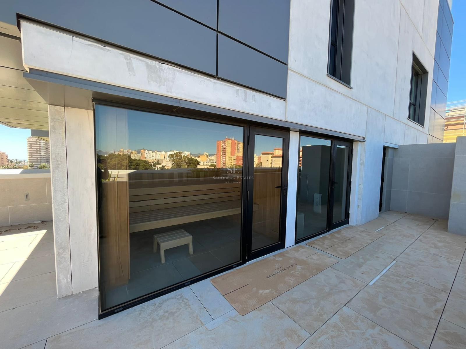 Exterior view of a terrace featuring a large glass-walled sauna with wooden interior seating.