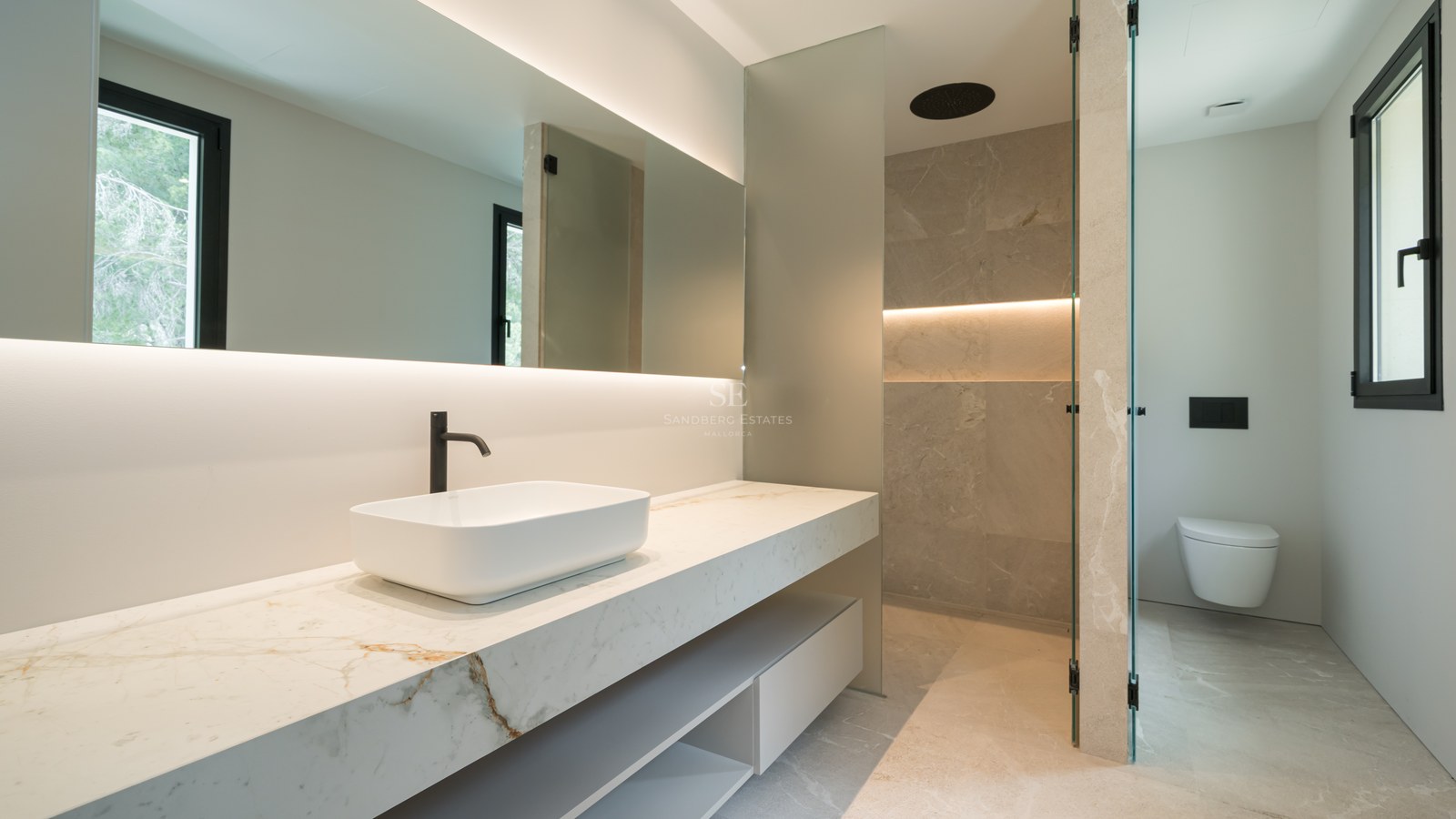 Baño contemporáneo con encimera de mármol, lavabo sobre encimera, ducha de efecto lluvia y sanitarios suspendidos.