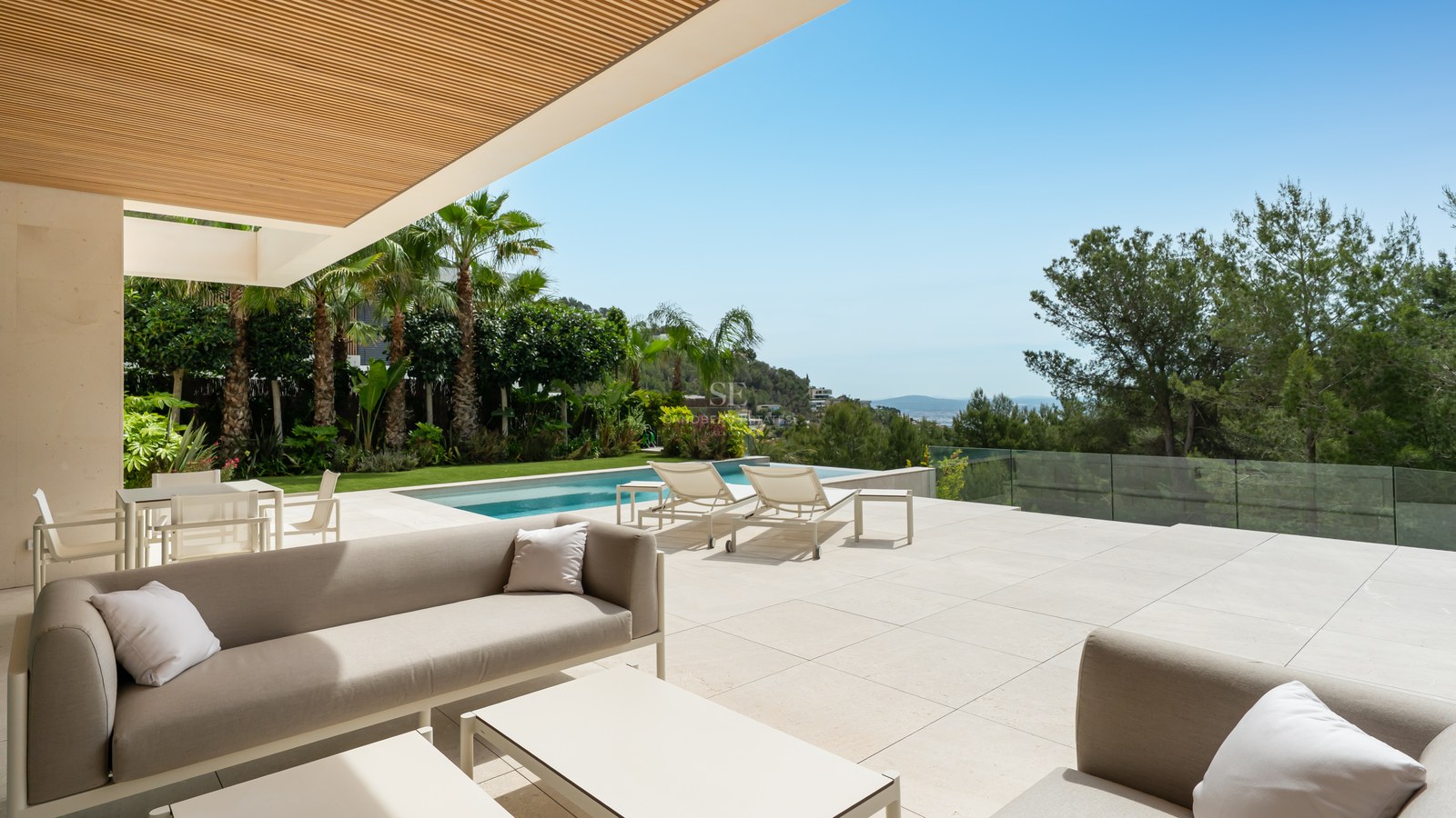 Terraza de lujo con suelo de piedra caliza, sofás de diseño, piscina infinita y vistas despejadas a la costa.