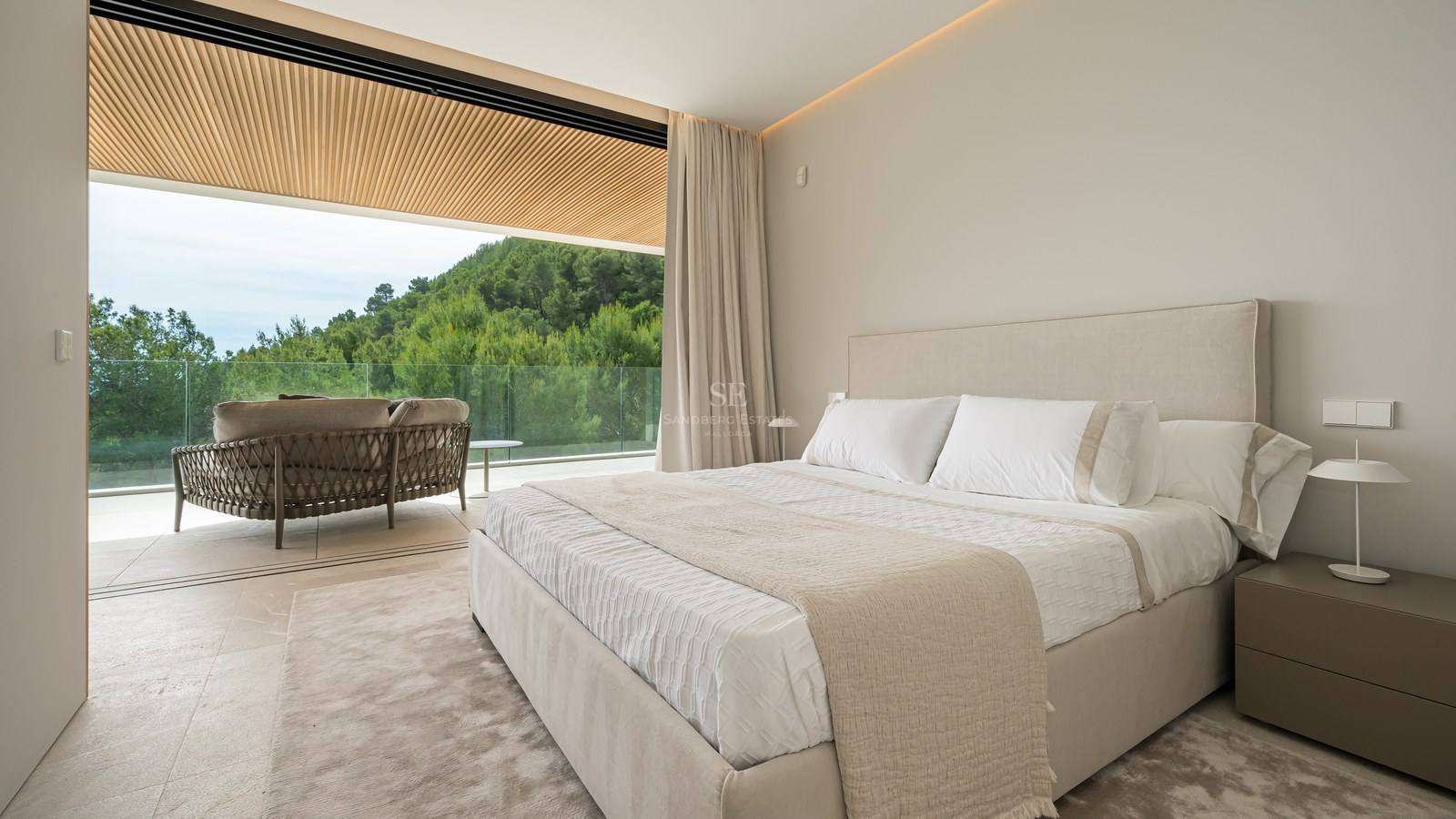 Suite principal contemporánea con puertas correderas que dan a una terraza con techo de madera y vistas al bosque.