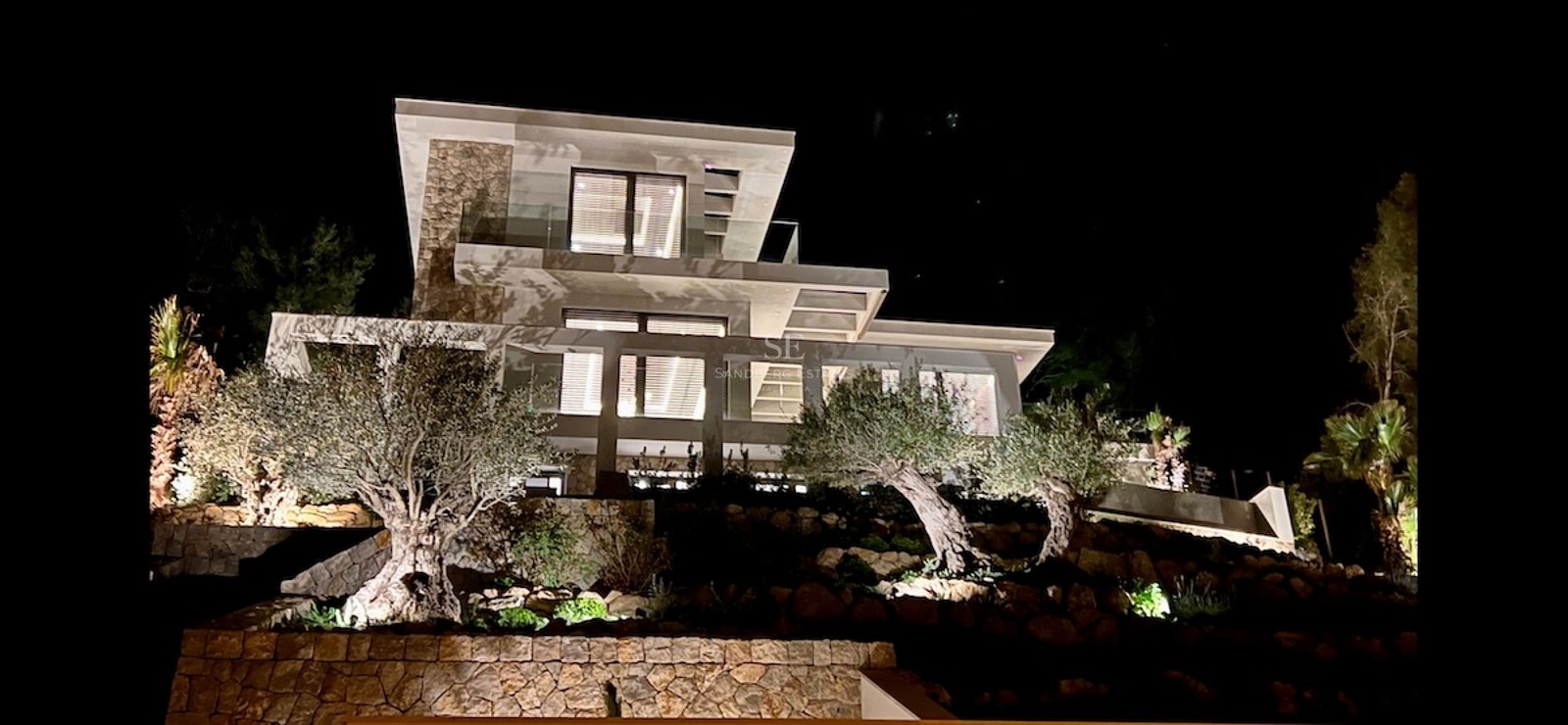 Imagen de chalet moderno con piscina, rodeado de vegetación. Diseño minimalista y acabados de lujo. Iluminación natural destacada.