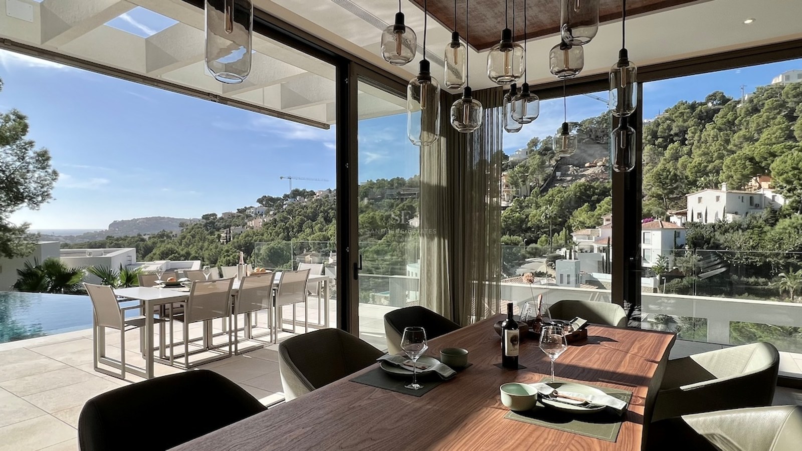 Amplia terraza con piscina infinita y vistas panorámicas al mar. Diseño moderno con mobiliario elegante y exuberante vegetación.