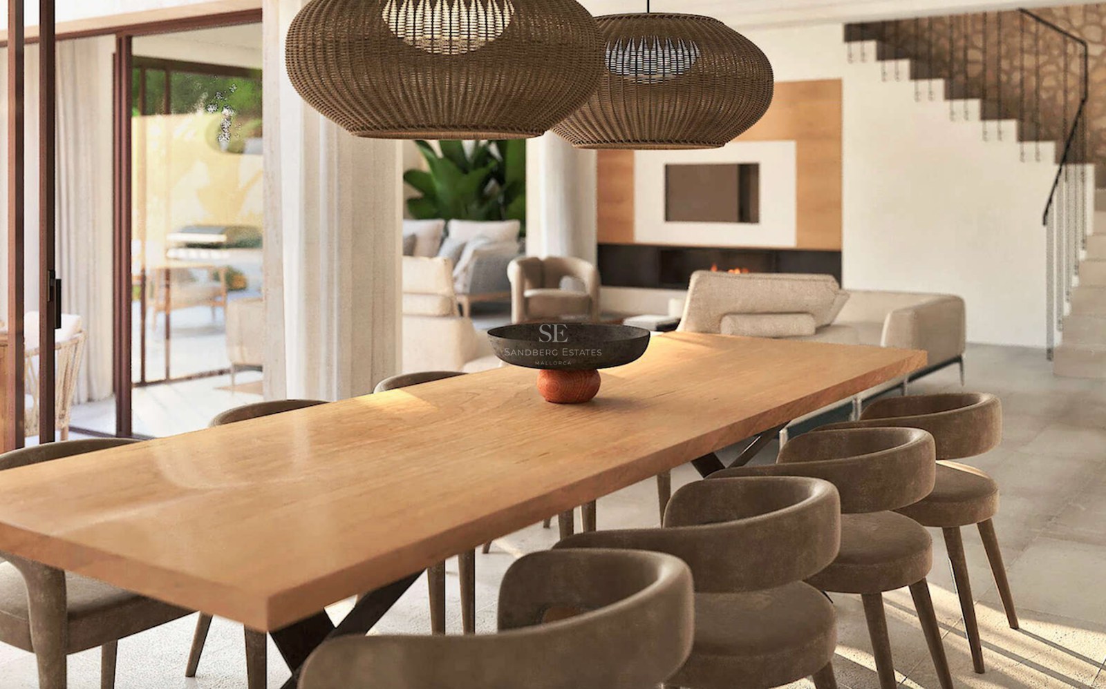 Salle à manger de luxe avec grande table en bois, chaises en velours et suspensions en rotin dans une villa ouverte.