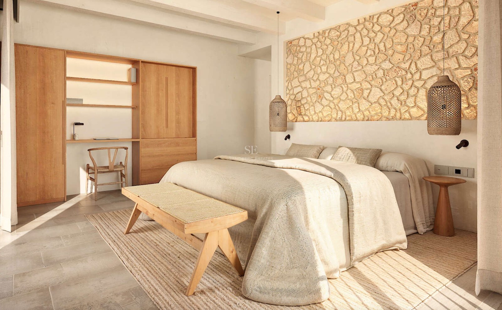 Chambre avec mur en pierre naturelle, bureau en bois et literie en lin sous une lumière naturelle vive.