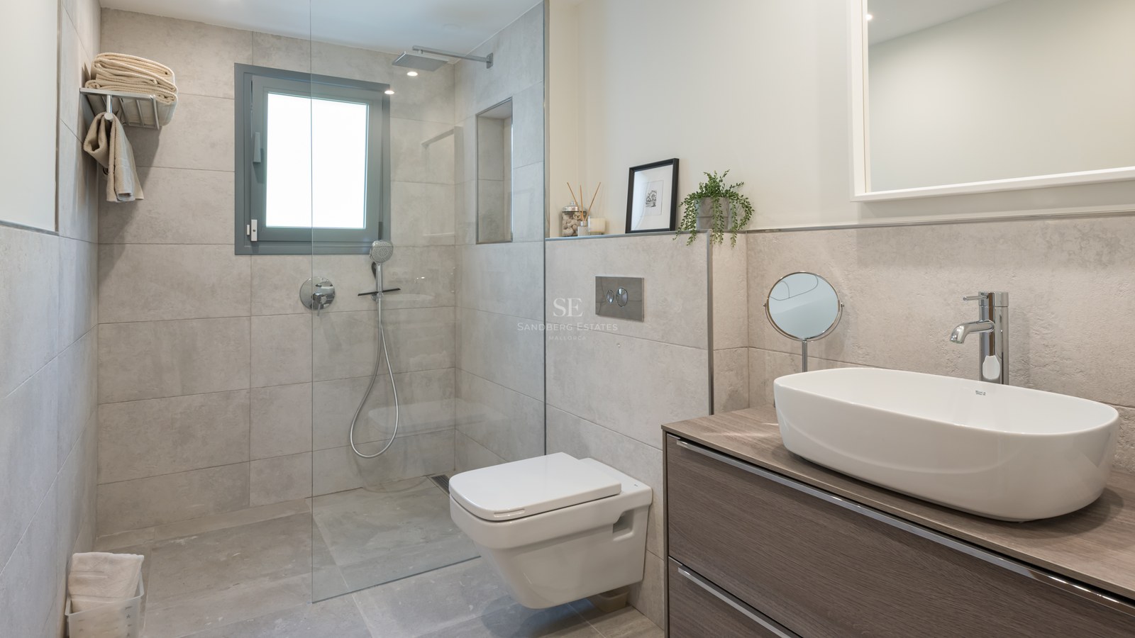 Modern bathroom featuring a glass walk-in shower, wall-hung toilet, and wooden vanity with a white vessel sink.
