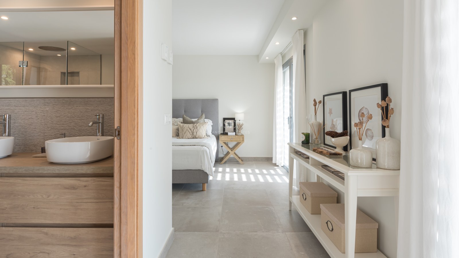 Modern master bedroom with grey bed and ensuite bathroom featuring a vessel sink and wooden vanity.