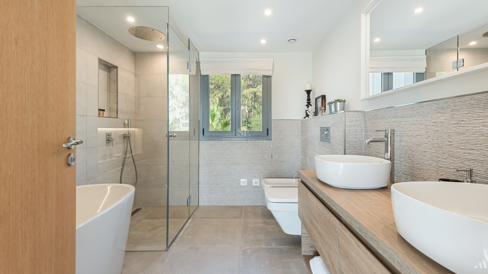 Modern bathroom featuring a glass walk-in shower, freestanding tub, and double vessel sinks on an oak vanity.
