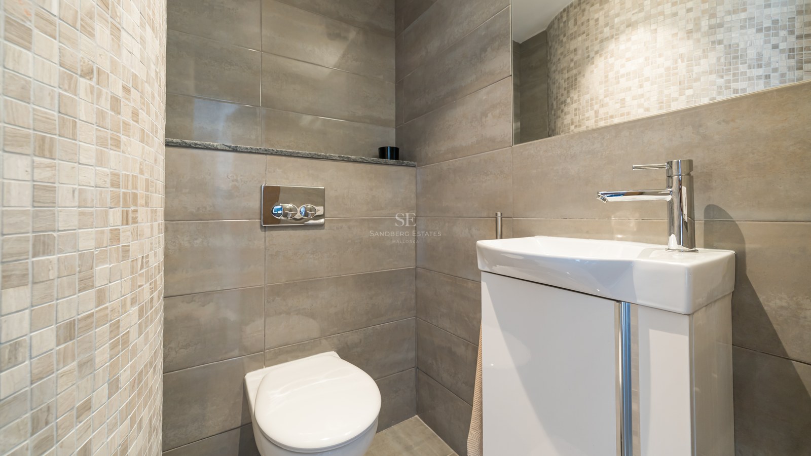 Aseo contemporáneo con azulejos grises, mueble blanco, grifo cromado y sanitario suspendido.
