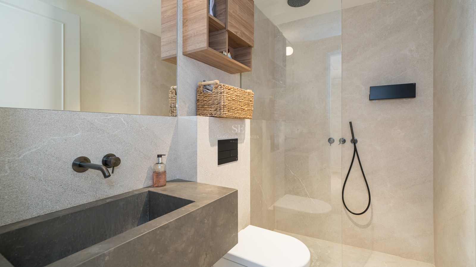 Modern bathroom with dark stone basin, wall-mounted black taps, and walk-in glass shower with beige stone tiles.